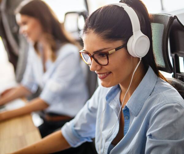 Friendly young woman helpline operator with headphones in call center